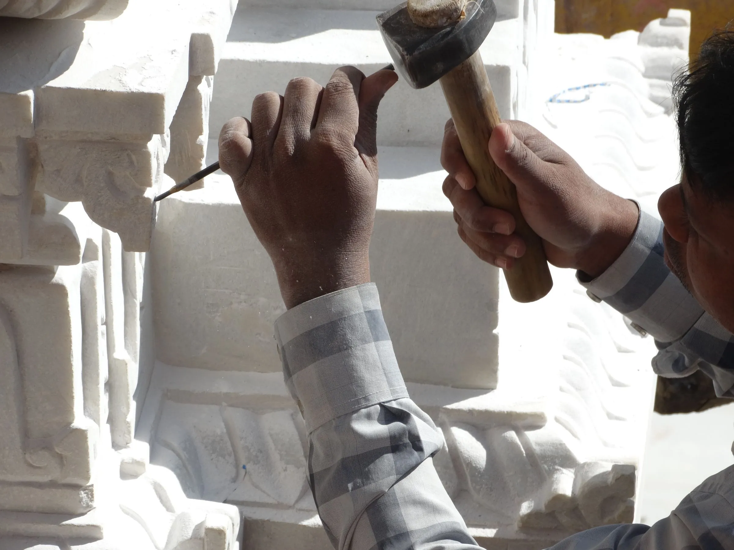 Artisan marbrier taillant un bloc de marbre blanc au ciseau