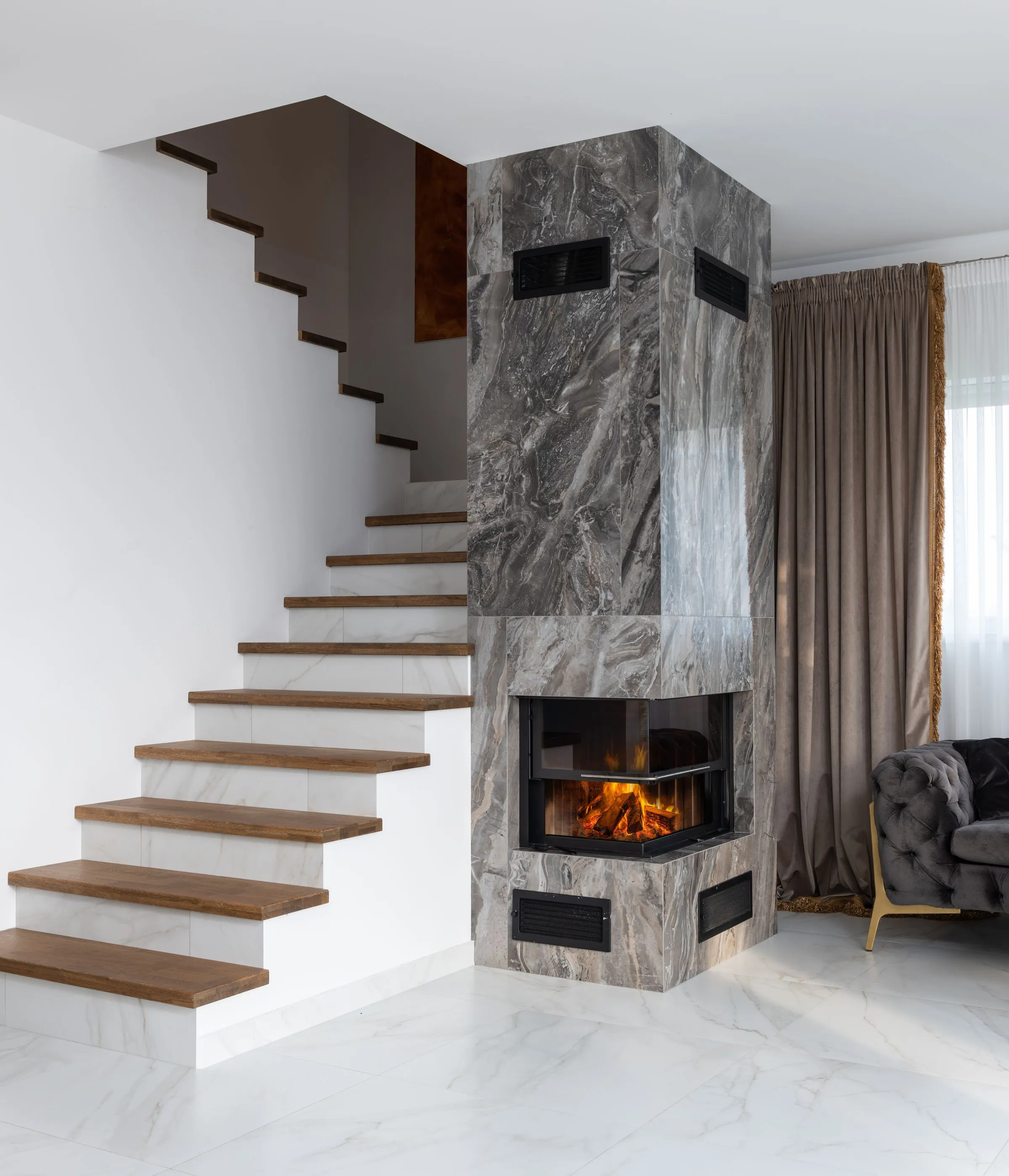 Intérieur de villa avec escalier en marbre et cheminée habillée de pierre